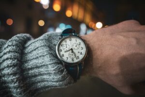 Chronograph watch with a white dial, being worn on a man with a gray sweater